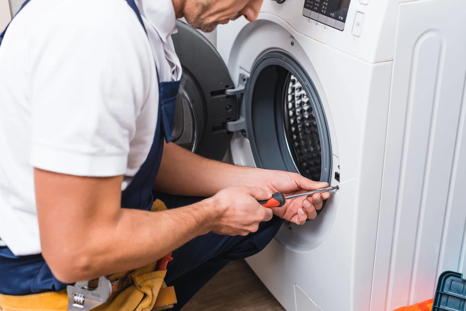 Technician using a screwdriver to make a precise repair on a washing machine